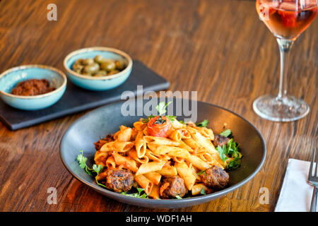 Penne Nudeln mit Hackfleischbällchen in Tomatensauce in einem schwarzen Schüssel Stockfoto