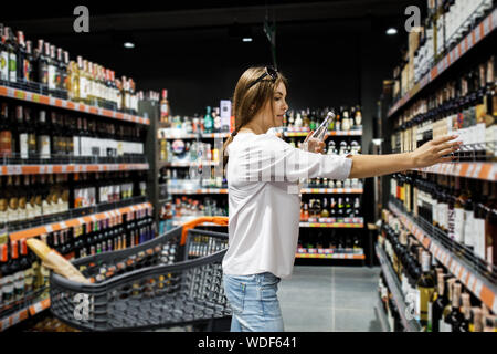 Junge hübsche Mädchen ist Einkaufen in einem großen Laden. Das Mädchen kauft Lebensmittel im Supermarkt. Stockfoto