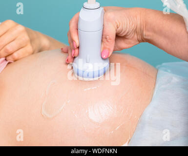 Sonograph Scannen der jungen schwangeren Bauch mit Ultraschallsensor, Geburtshilfe oder Schwangerschaft Ultraschall Verfahren Stockfoto