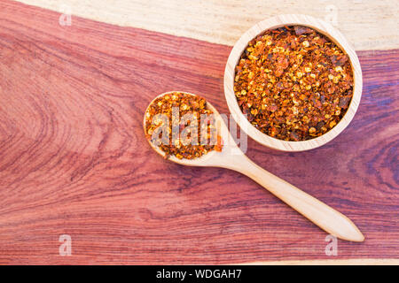 Spiced cayenne pfeffer in hölzerne Schüssel und Löffel auf den Tisch Hartholz. Wählen Sie konzentrieren. Stockfoto