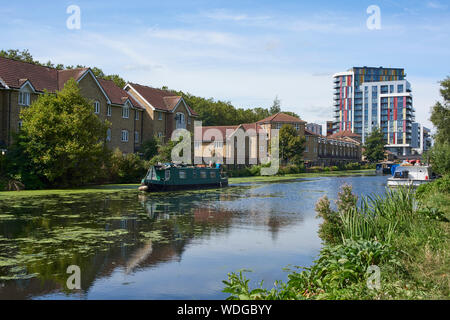 Den Fluss Lea Navigation in der Nähe von Lower Clapton, Hackney, London UK, im Sommer mit dem neuen Ehestifter Wharf Apartment Gebäude im Hintergrund Stockfoto