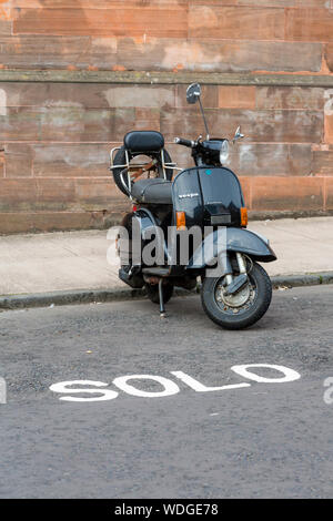 Eine Vespa Roller in der Bordstein geparkt Stockfoto