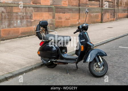 Eine Vespa Roller in der Bordstein geparkt Stockfoto