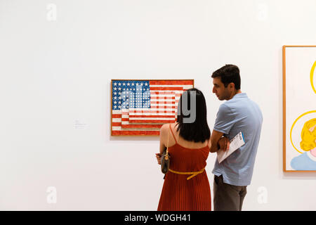 Whitney Museum, Ansicht der Rückseite zwei junge Menschen vor einem Gemälde von Jasper Johns (drei Flags), Whitney Museum der amerikanischen kunst, New York City. Stockfoto