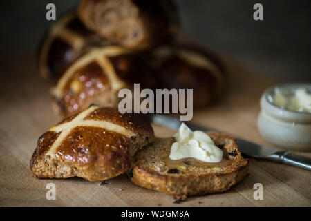 Hausgemachte Hot Cross Buns, Toast mit Butter. Stockfoto