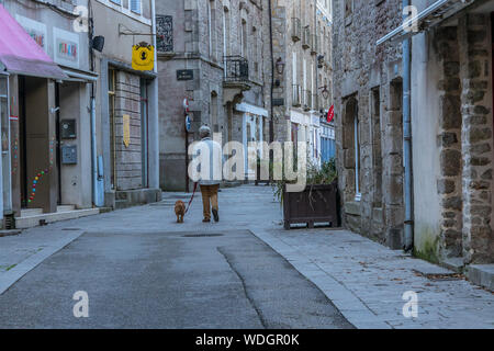 Mann, der seinen Hund in einem Straßen der Stadt Guérande in der französischen Bretagne. Oktober 15, 2018 Stockfoto