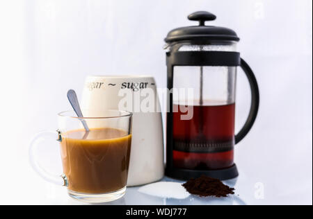 Eine Tasse Kaffee in einem Glas mug sitzt vor einem Zucker jar und eine Cafètiere halb voll mit Kaffee Stockfoto