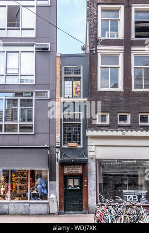 Amsterdam, Niederlande - 30. Juni 2019: Kleinste Haus und De Groene Lanteerne Restaurant in haarlemmerstraat zwischen zwei anderen Retail bu zusammengedrückt Stockfoto