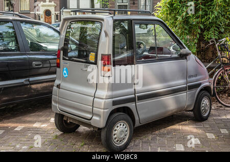 Amsterdam, Niederlande - 30. Juni 2019: Klein, Grau lackiert Mini Auto genannt Ganta GLX Canal geparkt. Grünes Laub. Stockfoto