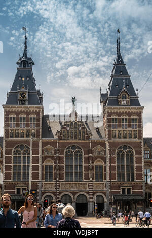 Amsterdam, Niederlande - 30. Juni 2019: monumentale Eingang Fassade mit Türmen in beige und roten Ziegeln. Statuen und Fresken. Unter blau-whtie Clo Stockfoto