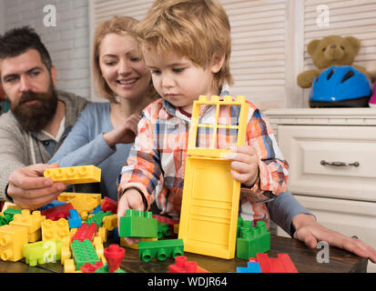 Junge Familie spielen mit Bau Kunststoff Bausteine. Familie spiele Konzept. Eltern mit glücklichen Gesichtern und Kid macht eine gemauerte Konstruktion. Vater, Mutter Stockfoto