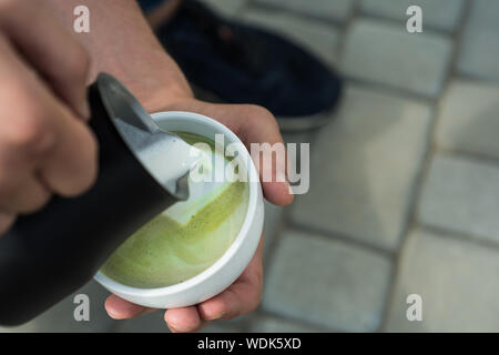 Matcha Latte Tee Zeremonie, Milch giessen. Barista gießen Sie Milch in japanischen Tee trinken. im Cafe oder im Café entspannen, trinken. Guten Morgen Kaffee. Perfekte morni Stockfoto