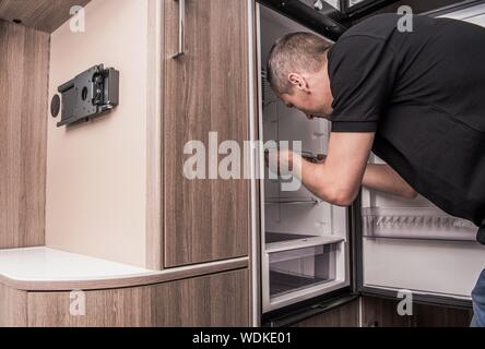 Wohnmobil Kühlschrank. Kaukasische Techniker in seinem 40s Austausch Reisemobil Kühlschrank. Camping und RVing Thema. Recreational Vehicle Appliances. Stockfoto