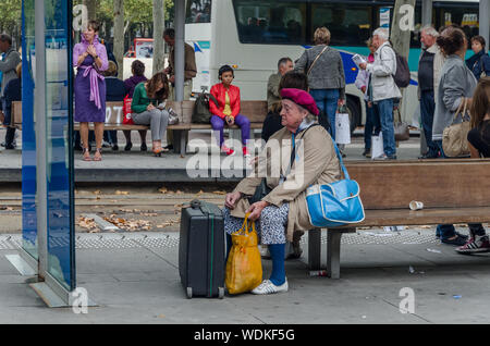 Dame mit Koffern und Taschen wartet auf den Bus in die Stadt Bordeaux, Frankreich, im September 2013 Stockfoto