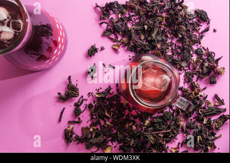 Hibiscus flower Tee, auch als Agua de Jamaica, Roselle, Sauerampfer und bissap bekannt. Getrocknete Hibiskusblüten lose auf rosa Hintergrund mit kühlem Eistee hibisc Stockfoto