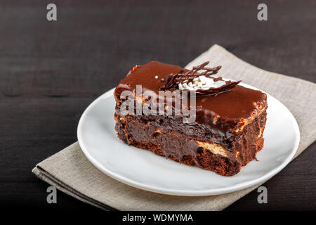 Teller mit einem Stück Schokolade Kuchen steht auf einem Holztisch Stockfoto