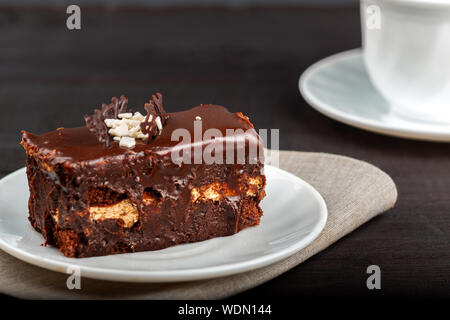 Teller mit einem Stück Schokolade Kuchen steht auf einem Holztisch Stockfoto