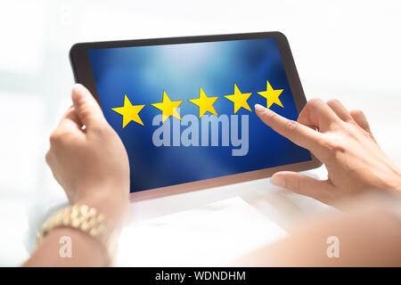 Frau mit positivem Feedback auf Tablet mit fünf gelben Stern auf dem Bildschirm Stockfoto