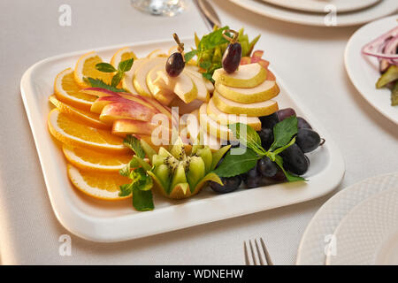 Teller mit geschnittenem Obst steht auf einem Tisch in einem Restaurant serviert. Stockfoto