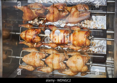 Ein paar ganze Hühner gebraten auf einem elektrischen Spieß Stockfoto
