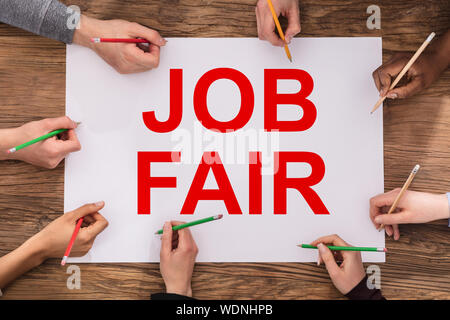Einen erhöhten Blick auf Geschäftsleute Hände Schreiben mit Bunte Bleistifte auf Job Fair Papier Stockfoto
