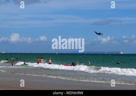 Bournemouth, UK. 29 Aug, 2019. Menschen spielen im Meer als Lancaster Bomber führt auf dem Bournemouth, Dorset, am 28. August 2019. Credit: Paul Marriott/Alamy leben Nachrichten Stockfoto