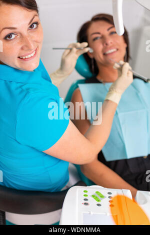 Erstaunlich, Lächeln, Blick von Oben auf die Zahnarzt seine schönen Patienten Prüfung in Zahnarzt s Büro. Stockfoto