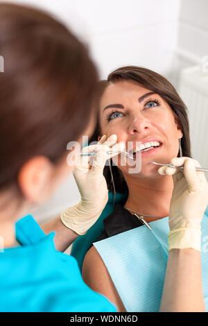 Erstaunlich, Lächeln, Blick von Oben auf die Zahnarzt seine schönen Patienten Prüfung in Zahnarzt s Büro. Stockfoto