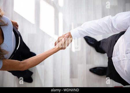 Eine erhöhte Ansicht des Geschäftsmannes Händeschütteln mit seinem Partner im Büro Stockfoto