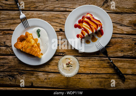 Zwei Scheiben Herbst Kürbis Kuchen mit Sahne und Marmelade Soße auf rustikalen Holztisch von oben. Essen Fotografie Konzept Stockfoto