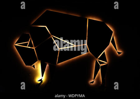 Glühende Leuchtreklame eines Stieres mit dunklem Hintergrund. Geeignet für Licht und Energie Themen. Stockfoto