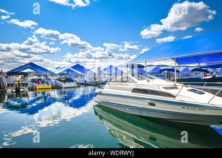 Ein teurer Luxus Speedboot sitzt in der Nähe der überdachten Boot Belege mit Booten auf der schwimmenden Steg des Coeur d'Alene Resort gefüllt Stockfoto