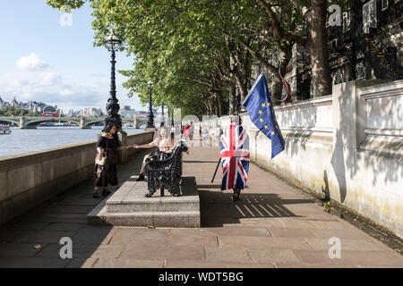 Ein anti Brexit Demonstrant das Tragen einer Union Flag und Durchführung einer EU-Flagge Spaziergänge durch einige Touristen am Südufer der Themse im Anschluss an eine Demonstration in London, Vereinigtes Königreich Stockfoto