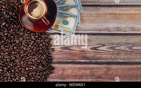 Amerikanischen Dollar und Kaffee Bohnen und Kaffee Tasse auf einem Holztisch Hintergrund. Stockfoto
