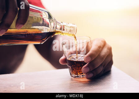 Gießt Whiskey oder Alkohol trinken aus der Flasche und Gläser auf Holz- Hintergrund/Likör Gießen Stockfoto