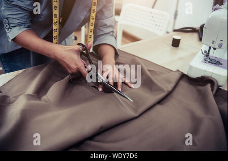 Schneiderin schneiden kleid Stoff auf Skizze Einklang mit der Nähmaschine. Fashion Designer anpassen oder Kanalsanierung in Workshop Studio entwerfen neue Kollektion Tuch Stockfoto