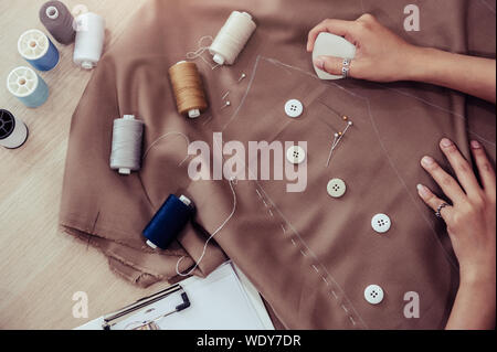 Blick von oben auf die schönen Schneiderin nähen Kleid Stoff mit Hand. Fashion Designer anpassen oder Kanalsanierung in Workshop Studio entwerfen neue Kollektion Kleidung. Stockfoto