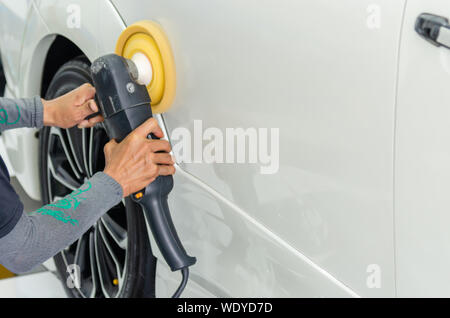 Mann bei der Arbeit Zum polieren, beschichten Autos. Polieren des Autos hilft Verunreinigungen auf der Oberfläche des Autos zu beseitigen. das Einwachsen der Auto Oberfläche c Stockfoto