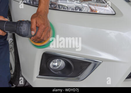 Mann bei der Arbeit Zum polieren, beschichten Autos. Polieren des Autos hilft Verunreinigungen auf der Oberfläche des Autos zu beseitigen. das Einwachsen der Auto Oberfläche c Stockfoto
