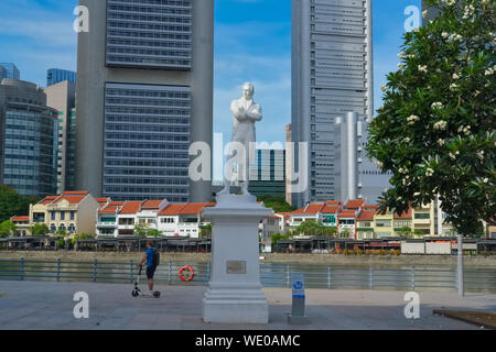 Ein Mann auf einem e-Scooter Fahrgeschäfte Vergangenheit das Wahrzeichen "Raffles Statue am Raffles Landing Site, North Boat Quay, durch den Fluss Singapur, Singapur Stockfoto