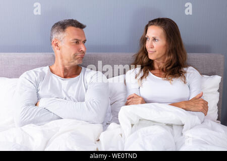 Portrait von traurigen Paar sitzt auf Bett mit weißer Decke Stockfoto