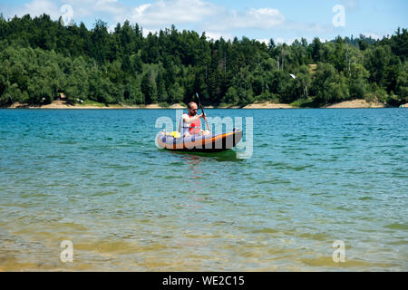 Mann Kajak in aufblasbare Kajak fahren auf dem See, in Lokve Gorski kotar, Kroatien. Abenteuerliche Erfahrung an einem schönen sonnigen Tag. Stockfoto