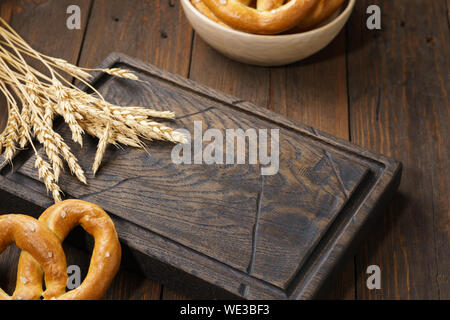 Brezeln und Weizen auf einem dunklen Holzmöbeln serviert. Bier snacks Hintergrund. Kopieren Sie Platz. Stockfoto
