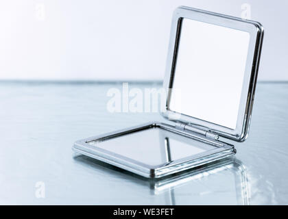 Kleine Pocket Mirror auf Glas Tisch Hintergrund. Eleganz Weibliche Accessoire. Stockfoto