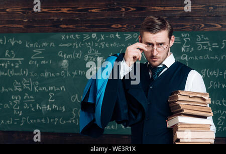 Junge Professor holding Stapel Bücher über seine Brille. Aristocrat Gelehrter in der Elite der Hochschule. Stockfoto