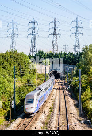 Ein doppeldecker TGV Duplex Hochgeschwindigkeitszug in Atlantik livery ist in einen Tunnel unter einer Reihe von Sendemasten auf der LGV Atlantique Eisenbahn. Stockfoto