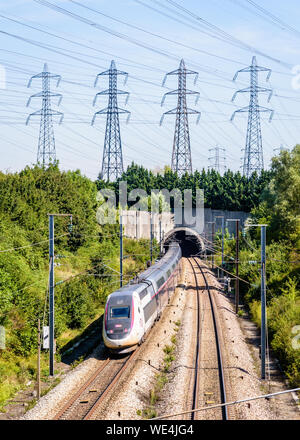 Ein doppeldecker TGV Duplex Hochgeschwindigkeitszug in Carmillon livery ist in einen Tunnel unter einer Reihe von Sendemasten auf der LGV Atlantique Eisenbahn. Stockfoto