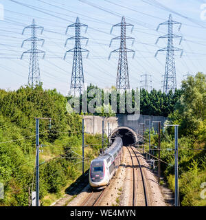 Ein doppeldecker TGV Duplex Hochgeschwindigkeitszug in Carmillon livery ist in einen Tunnel unter einer Reihe von Sendemasten auf der LGV Atlantique Eisenbahn. Stockfoto