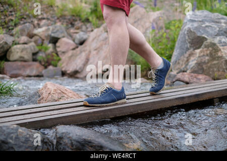 Mann auf einer hölzernen Brücke über Wasser Stream auf Sommer Tag Stockfoto