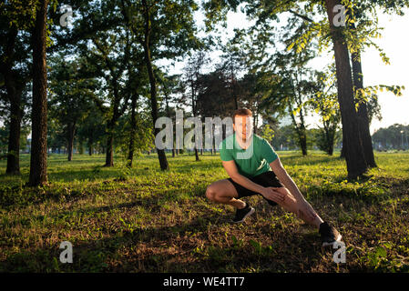 Junger Mann sich die Beine während Outdoor Training in einem Park Stockfoto